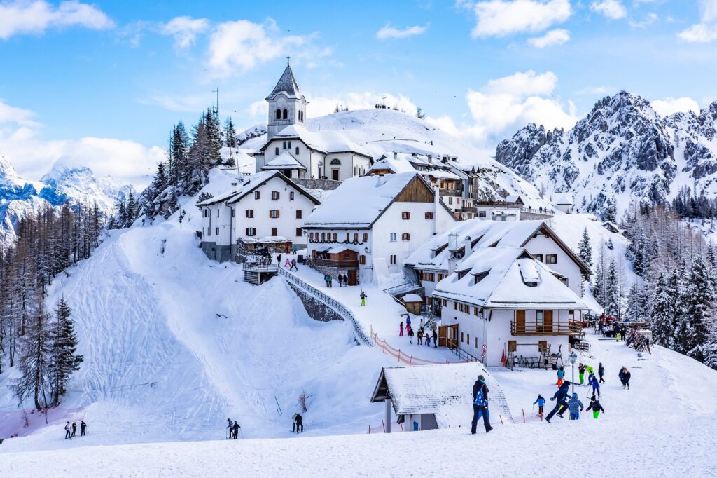 Paese alpino innevato con la chiesa e le piste