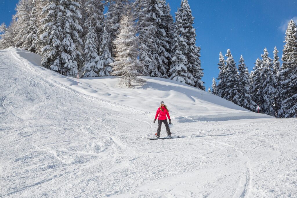 Sciatrice su una pista tra gli abeti innevati
